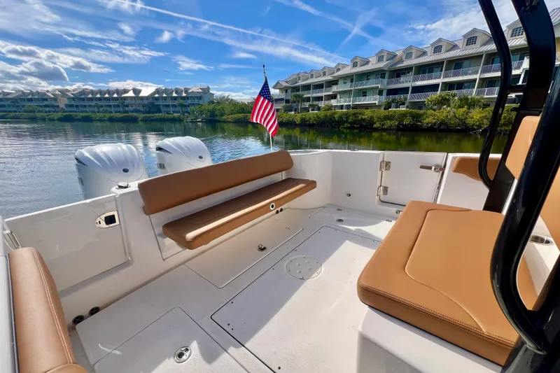 Slide: The Image of 2025 Robalo R302 Center Console boat with seating, docked by waterfront homes. - 10