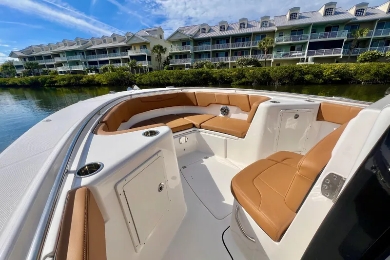 Slide: The Image of 2025 Robalo R302 Center Console boat with tan seating, docked near waterfront condos. - 16