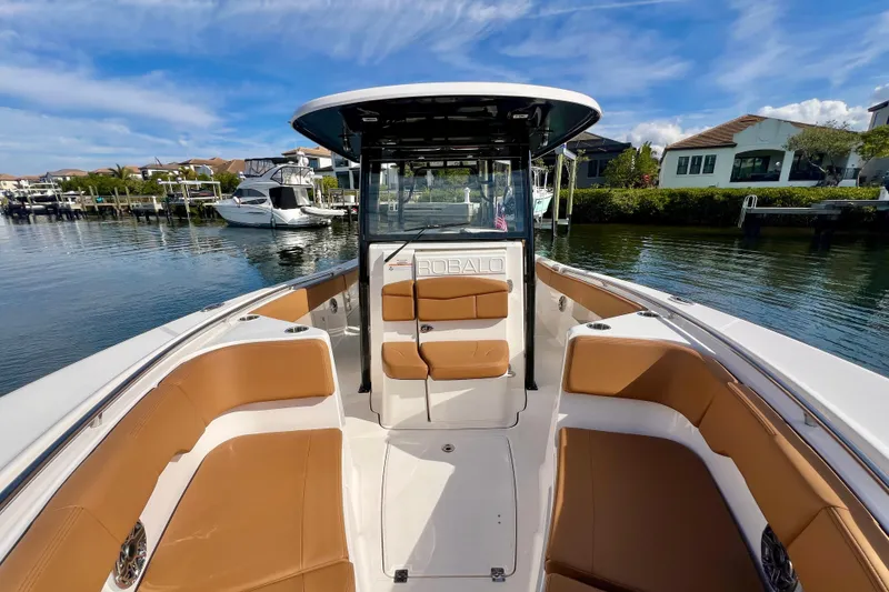 Slide: The Image of 2025 Robalo R302 Center Console boat with tan seating, docked in a scenic marina. - 21
