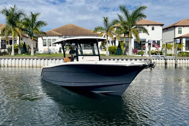 Slide: The Image of 2025 Robalo R302 Center Console boat on water, with palm trees and houses in background. - 5