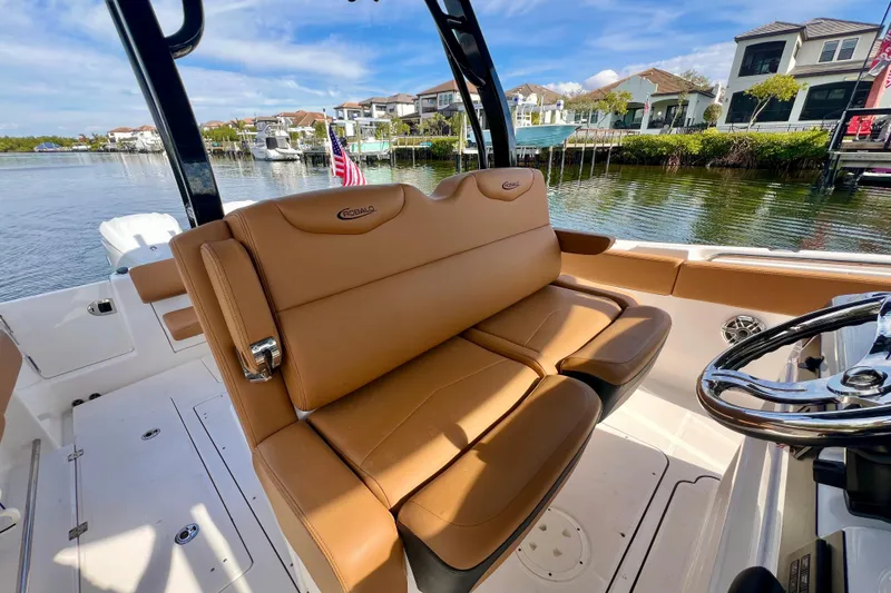 Slide: The Image of 2025 Robalo R302 Center Console boat interior with tan seating, dockside view. - 14