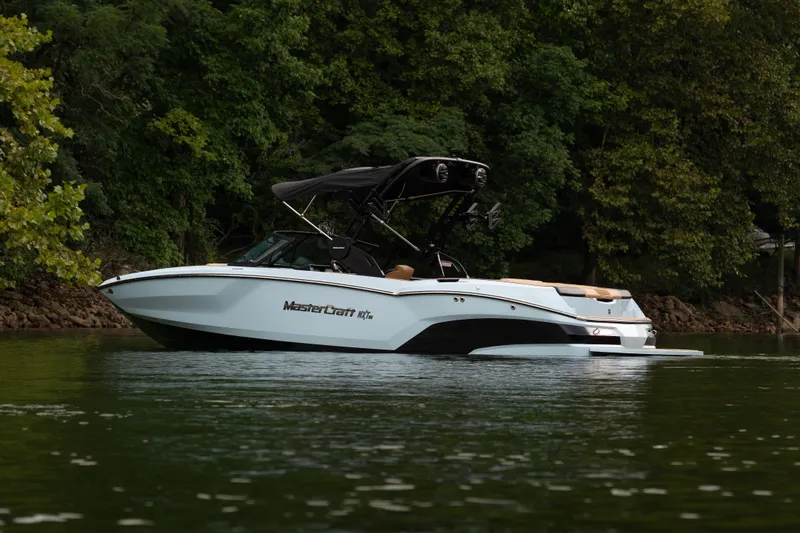 Slide: The Image of 2026 MasterCraft NXT23 boat on a serene lake, surrounded by lush greenery. - 3