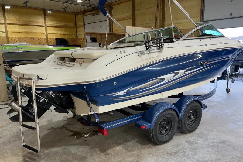 Slide: The Image of 2004 Sea Ray 200 Select boat in a garage, blue and white design, on a trailer. - 3