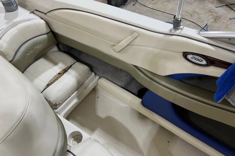Slide: The Image of 2004 Sea Ray 200 Select boat interior with worn seating and visible logo. - 15