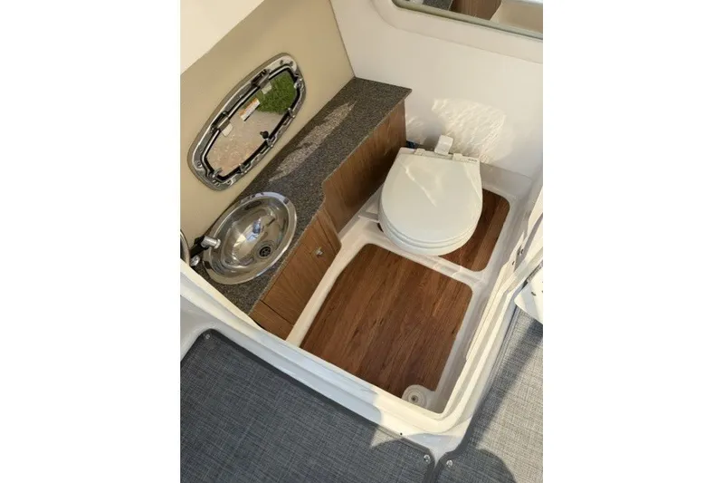 Slide: The Image of 2015 Chaparral 257 SSX boat interior with sink and toilet, featuring wood accents. - 13