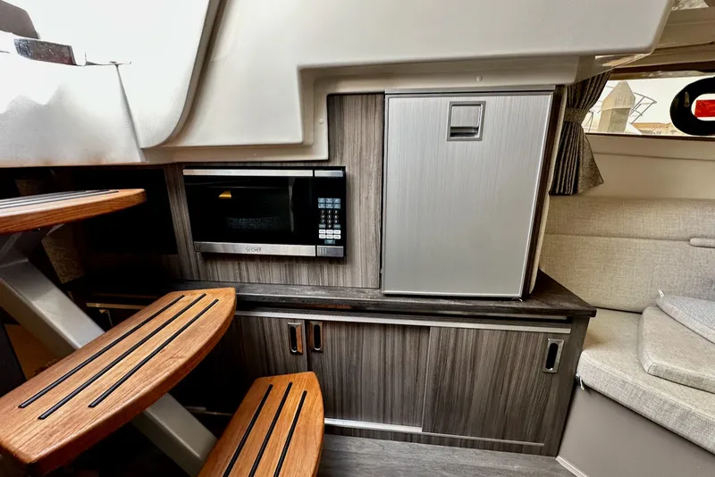 Slide: The Image of The cabin of the 2021 Sea Ray Sundancer 320 Outboard features a microwave and a refrigerator. - 31