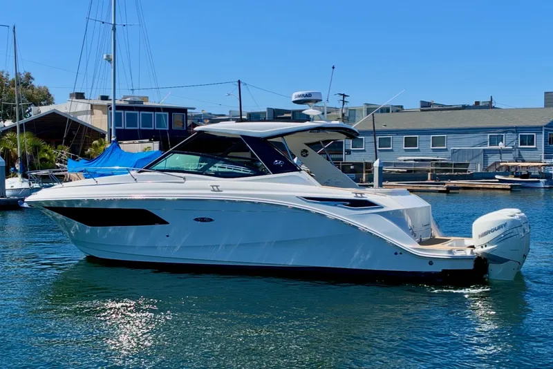 Slide: The Image of A 2021 Sea Ray Sundancer 320 Outboard is anchored in the water, surrounded by buildings. - 2