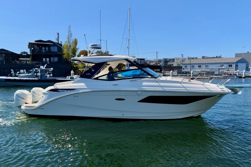 Slide: The Image of A 2021 Sea Ray Sundancer 320 Outboard cruising on calm water. It features a sleek, modern design. - 12