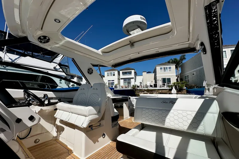 Slide: The Image of The image shows the cockpit of a 2021 Sea Ray Sundancer 320 Outboard with luxurious seating and an open roof. - 16