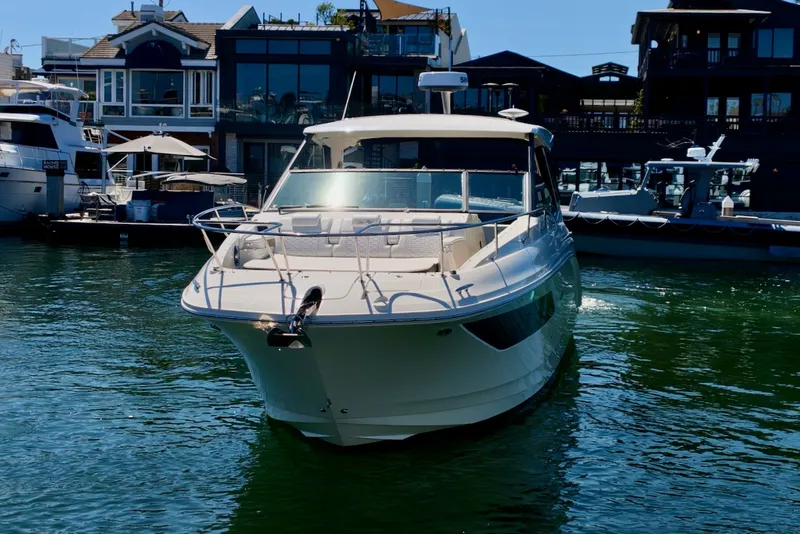 Slide: The Image of A 2021 Sea Ray Sundancer 320 Outboard is docked in the water near a marina. - 10