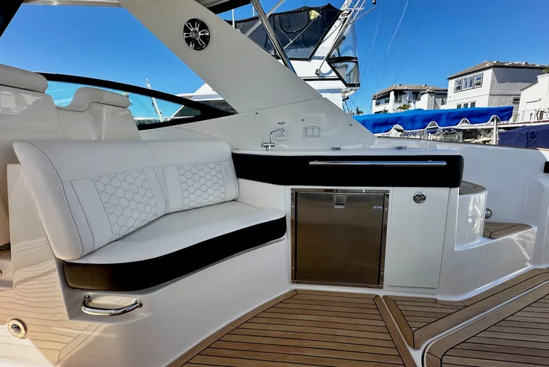Slide: The Image of The image shows the cockpit of a 2021 Sea Ray Sundancer 320 Outboard with sleek white seating and a refrigerator. - 22