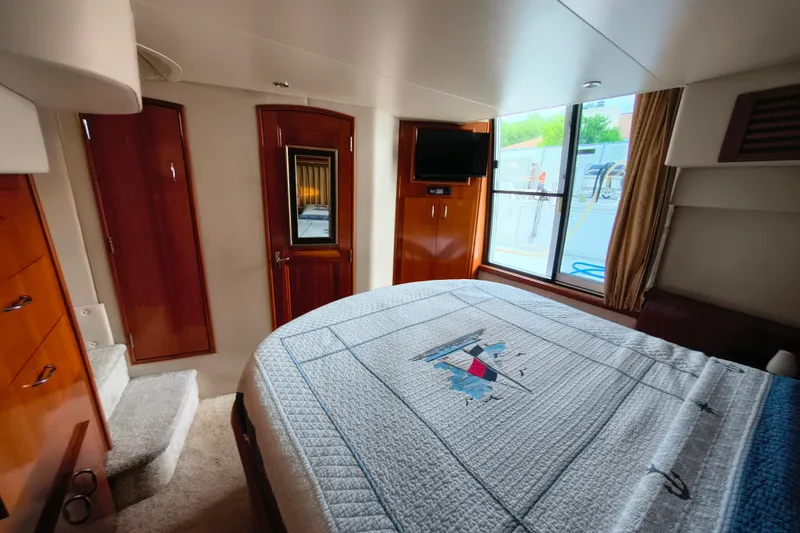 Slide: The Image of Interior of 2006 Carver 444 Cockpit Motor Yacht bedroom with bed, window, and wooden cabinetry. - 32