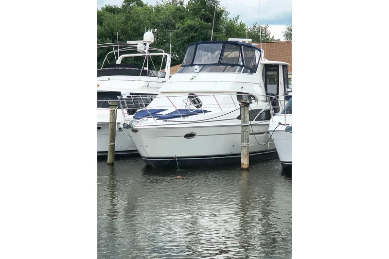 The Image of 2006 Carver 444 Cockpit Motor Yacht docked in a marina, surrounded by water and other boats. - 6