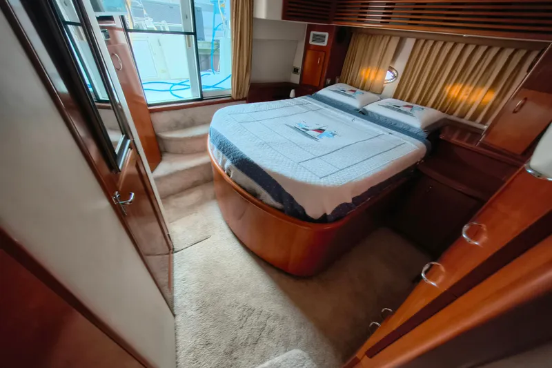 Slide: The Image of 2006 Carver 444 Cockpit Motor Yacht bedroom with cozy bed and elegant wood finish. - 29