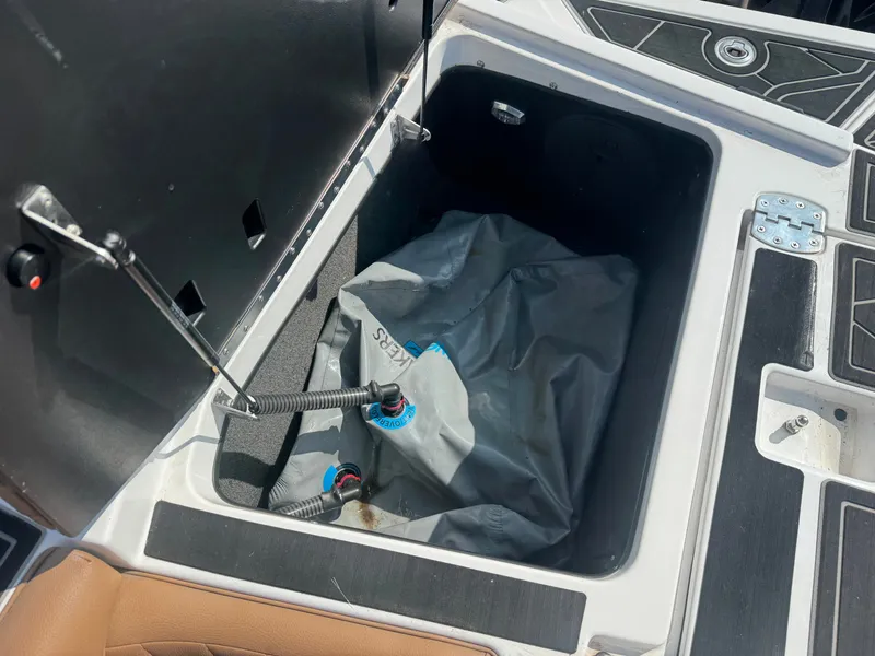 Slide: The Image of An open storage compartment on a 2022 Tigé 20 RZX boat with a gray bag inside. - 33