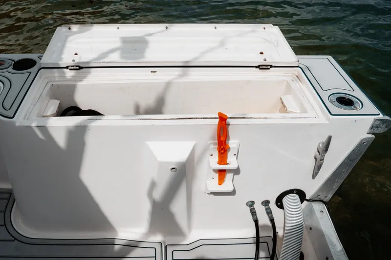 Slide: The Image of Open storage compartment on a 1996 Mako 231 Center Console boat by the water. - 38