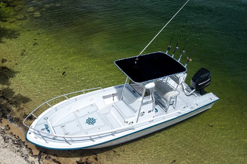 The Image of 1996 Mako 231 Center Console boat in clear shallow water, equipped with fishing rods. - 0