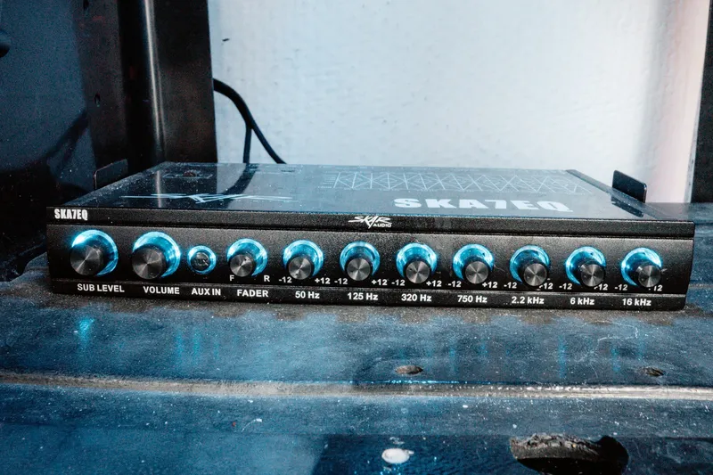 Slide: The Image of Audio equalizer with multiple frequency knobs and blue accents on a black surface. - 22