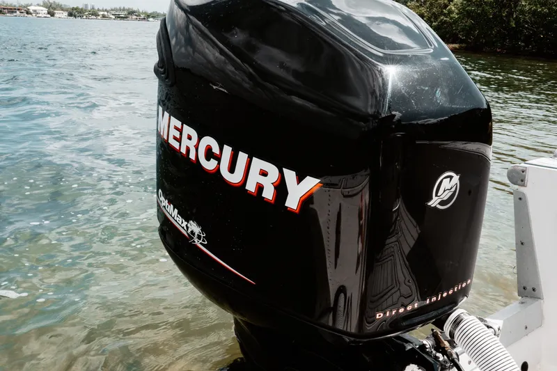 Slide: The Image of Mercury OptiMax engine on a 1996 Mako 231 Center Console boat by the water. - 13