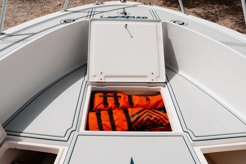 Slide: The Image of Open storage compartment on 1996 Mako 231 Center Console boat with orange life jackets. - 28
