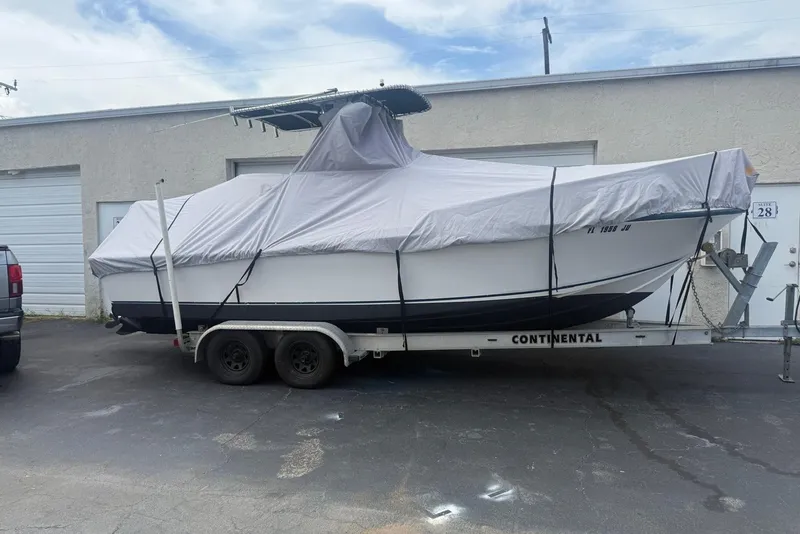 Slide: The Image of Covered 1996 Mako 231 Center Console boat on trailer, parked outside a garage. - 4