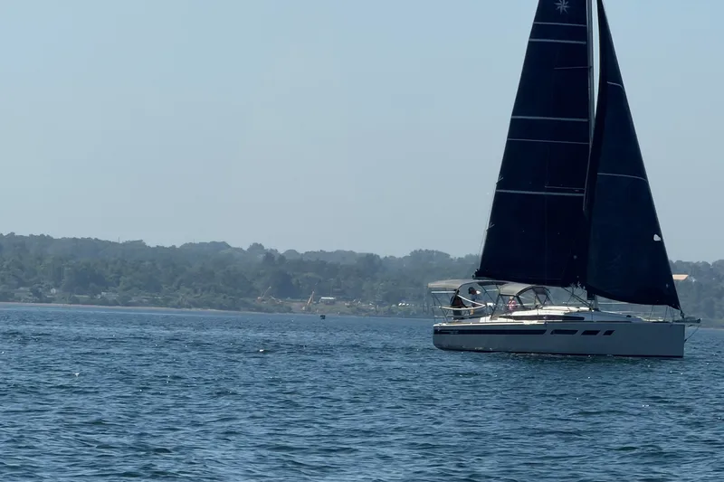 Slide: The Image of 2022 Jeanneau Sun Odyssey 349 Performance sailing on calm waters near a forested shoreline. - 33
