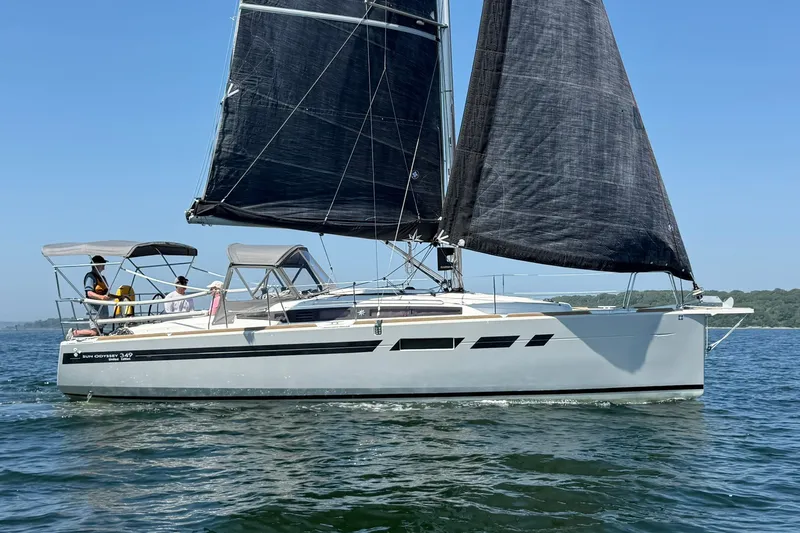 Slide: The Image of 2022 Jeanneau Sun Odyssey 349 Performance sailboat on water, featuring sleek design and black sails. - 37