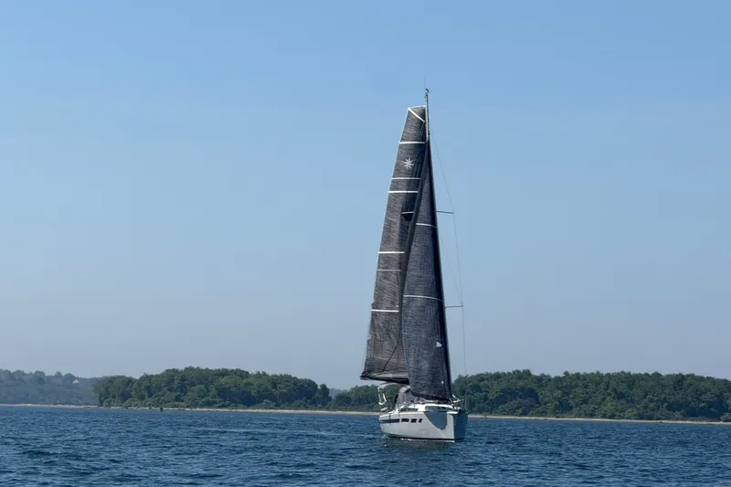 Slide: The Image of 2022 Jeanneau Sun Odyssey 349 Performance sailing on open water with lush shoreline backdrop. - 34