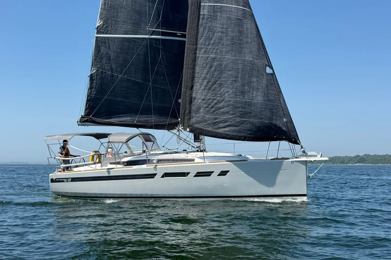Slide: The Image of 2022 Jeanneau Sun Odyssey 349 Performance sailboat on open water, featuring sleek black sails. - 51