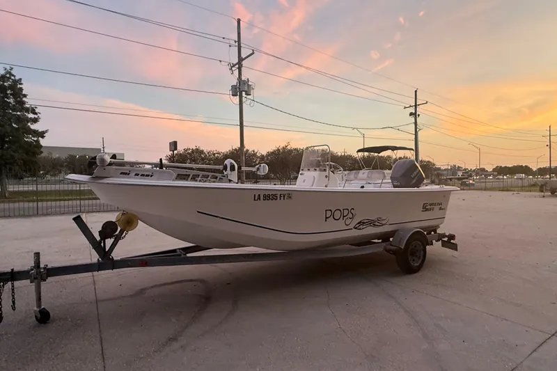Slide: The Image of 2011 Carolina Skiff 218 DLV boat on trailer at sunset, labeled "POPS." - 7