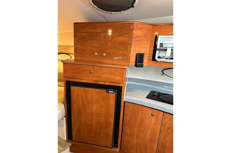 Slide: The Image of 2005 Larson Cabrio 310 interior with wooden cabinetry and compact kitchen amenities. - 5