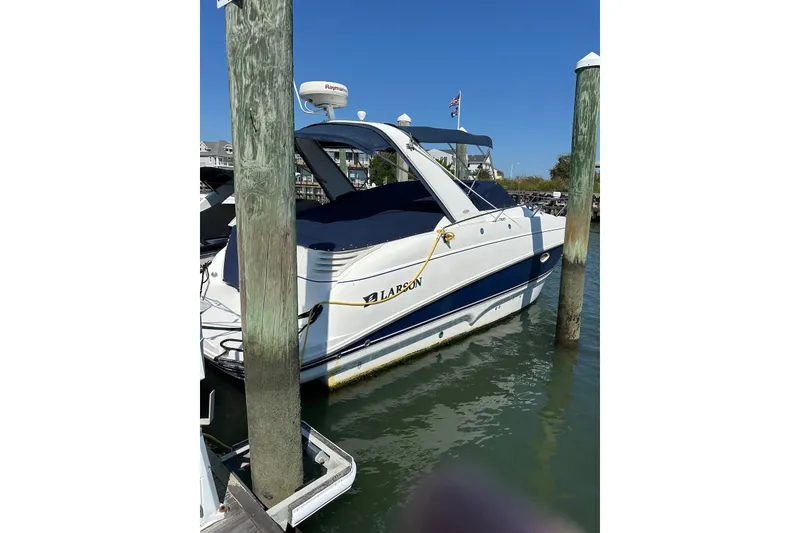 Slide: The Image of 2005 Larson Cabrio 310 boat docked in marina, clear blue sky. - 2