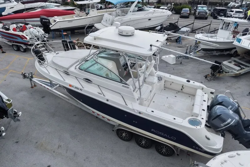 Slide: The Image of 2011 Robalo R305 Walkaround boat on trailer, parked in a marina with other boats. - 8