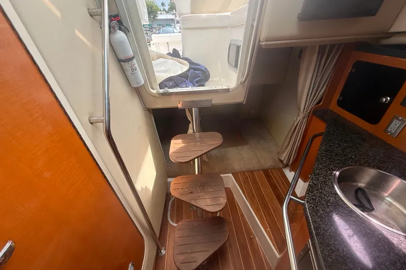 Slide: The Image of Interior view of a 2011 Robalo R305 Walkaround boat with wooden steps and kitchenette. - 47