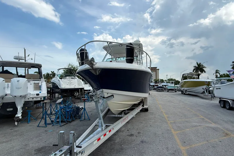 Slide: The Image of 2011 Robalo R305 Walkaround boat on trailer in marina under cloudy sky. - 6