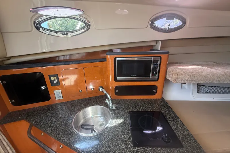 Slide: The Image of 2011 Robalo R305 Walkaround cabin with kitchenette, featuring sink, microwave, and stove. - 39