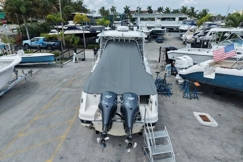 Slide: The Image of 2011 Robalo R305 Walkaround boat with cover, parked in a marina with other boats. - 4