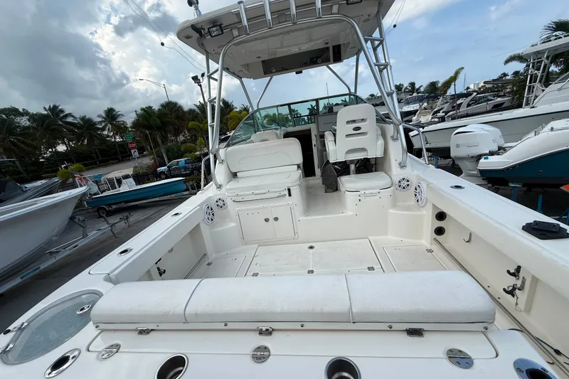 Slide: The Image of 2011 Robalo R305 Walkaround boat interior with seating and helm, docked under cloudy skies. - 13