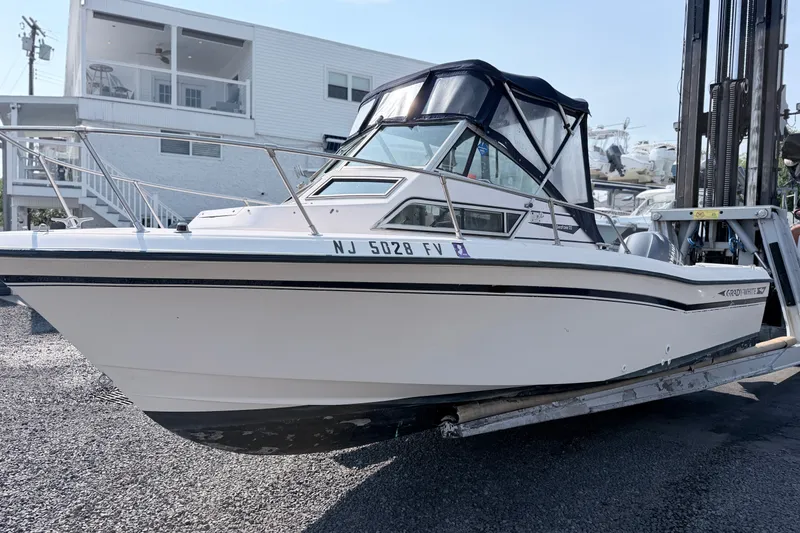 The Image of 1993 Grady-White Seafarer 22 boat on a lift, with a white exterior and black canopy. - 0