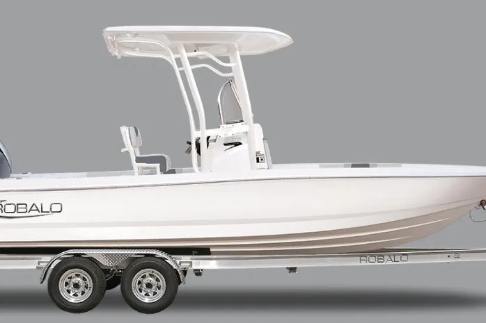 The Image of 2027 Robalo 226 Cayman boat on trailer, side view, white hull, T-top, gray background. - 0
