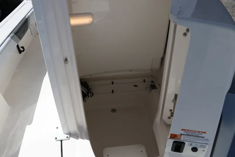 Slide: The Image of Interior storage compartment of 2027 Robalo 226 Cayman boat, featuring white finish and secure latch. - 21