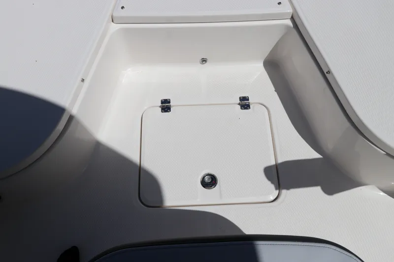 Slide: The Image of 2027 Robalo 226 Cayman boat storage compartment with white interior and secure latch. - 26