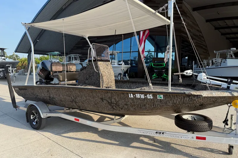 Slide: The Image of 2024 Xpress H190B Bay boat with canopy on trailer, parked outside a showroom. - 3
