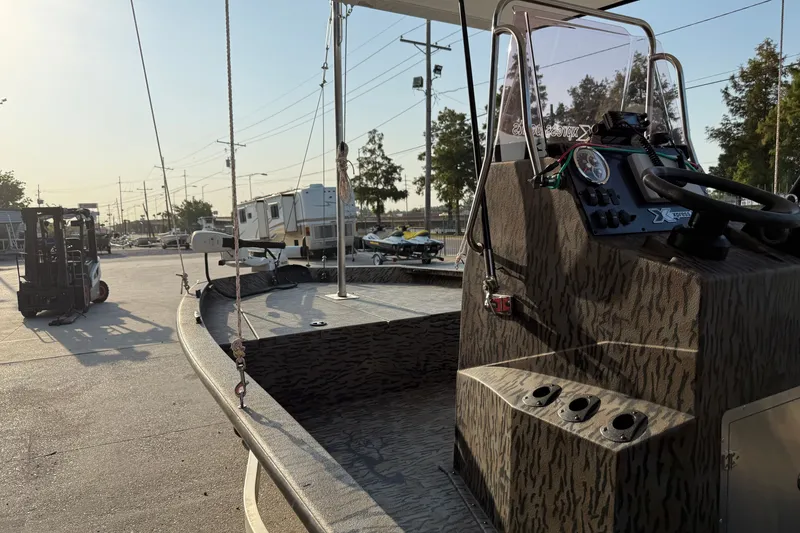 Slide: The Image of 2024 Xpress H190B Bay boat with camo design, parked outdoors in a sunny setting. - 12
