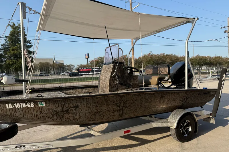 Slide: The Image of 2024 Xpress H190B Bay boat with canopy on trailer, parked outdoors. - 8