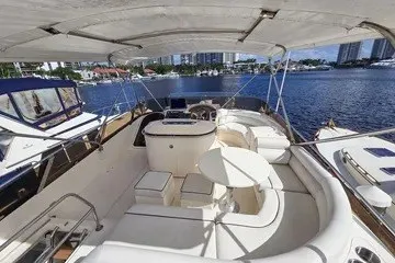 Slide: The Image of 1998 Viking Princess 56 Sport Cruiser yacht interior with seating and helm, docked by waterfront. - 9