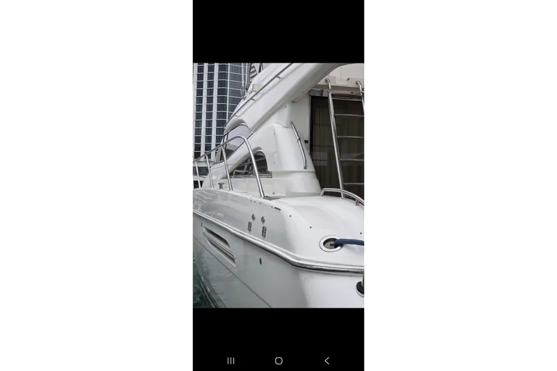 Slide: The Image of 1998 Viking Princess 56 Sport Cruiser yacht docked near modern buildings. - 36