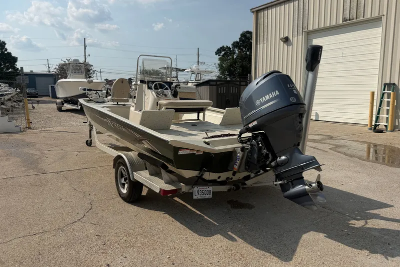 Slide: The Image of 2013 Xpress H20B Bay boat with Yamaha outboard motor parked outside a warehouse. - 6