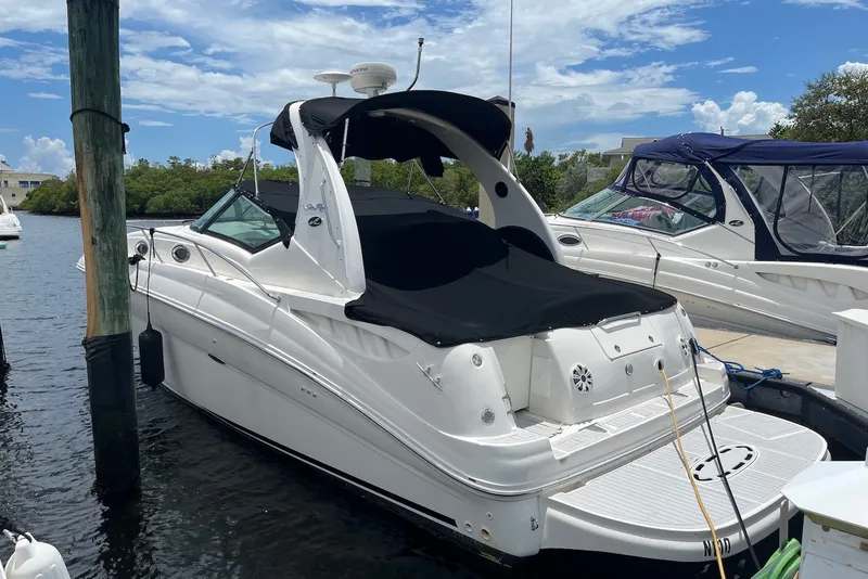 The Image of 2003 Sea Ray Sundancer 320 docked, featuring sleek design and black cover under a blue sky. - 0