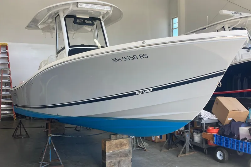 Slide: The Image of 2022 Regulator 26XO boat in a garage, elevated on stands, with visible registration number. - 20